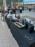 Load image into Gallery viewer, A table at an outdoor event displaying a variety of hats and accessories, presumably part of a hat bar service.