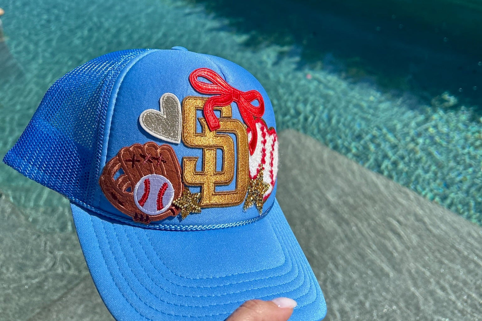 Blue cap with various patches held over a pool
