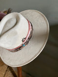 Load image into Gallery viewer, Elevate your style with The Bre, an ivory flat brim rancher hat crafted from vegan suede, featuring a striking snake skin print, blush-tone recycled silk from India, and finished with a feather and sun brand. Shop now at Harper & Honey for a chic and unique statement piece!